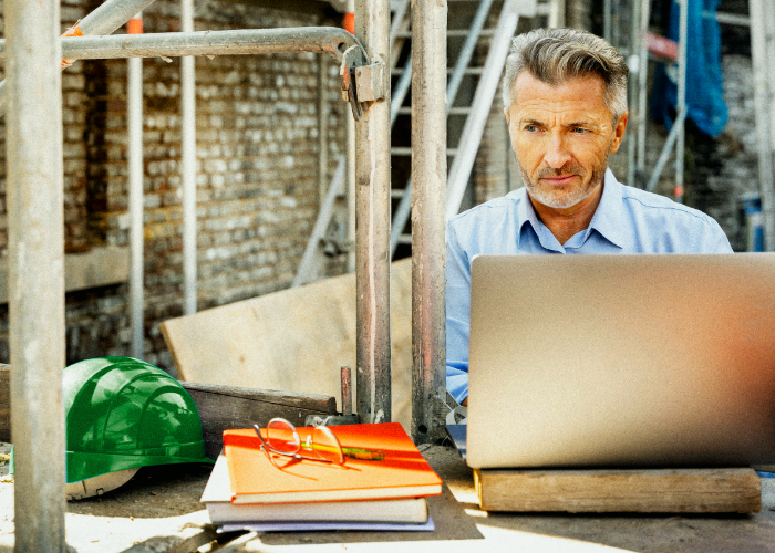 man in construction site using a laptop