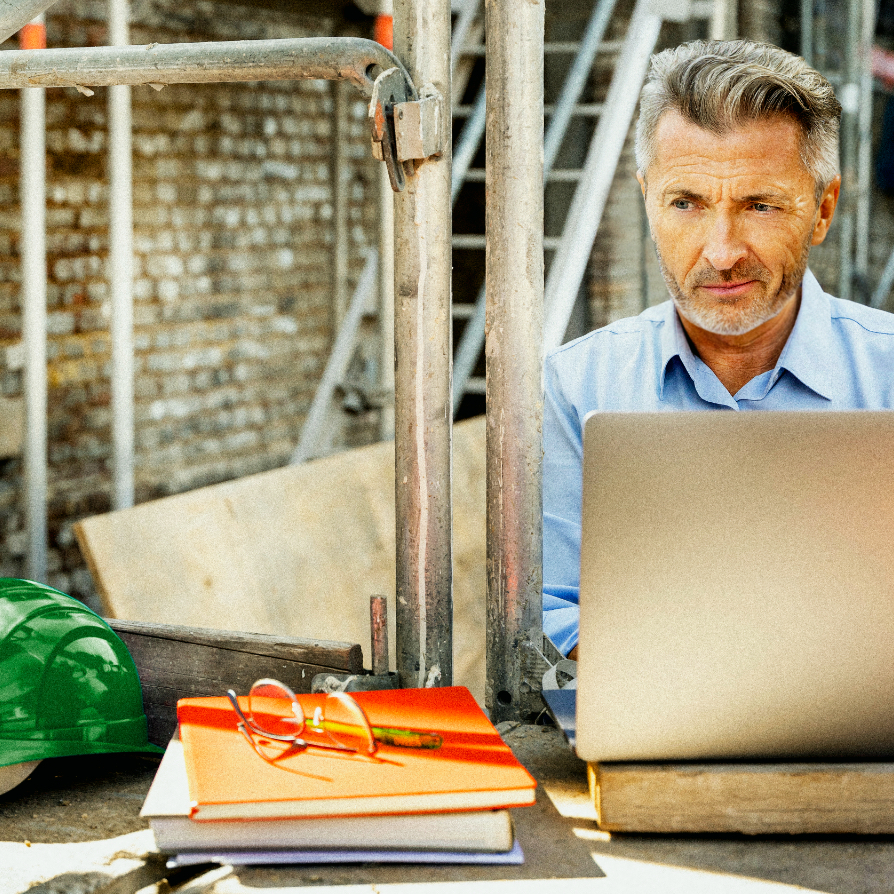 man in construction site using a laptop