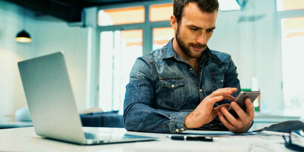 man in an office using his phone